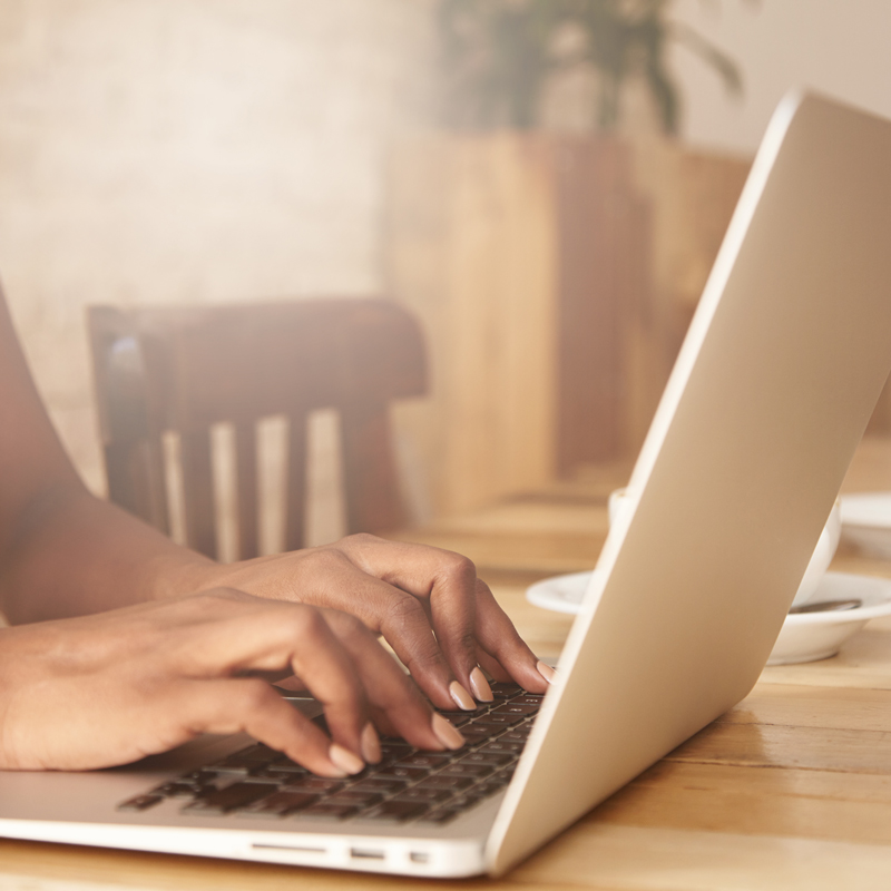 Foto de mãos digitando em um notebook.