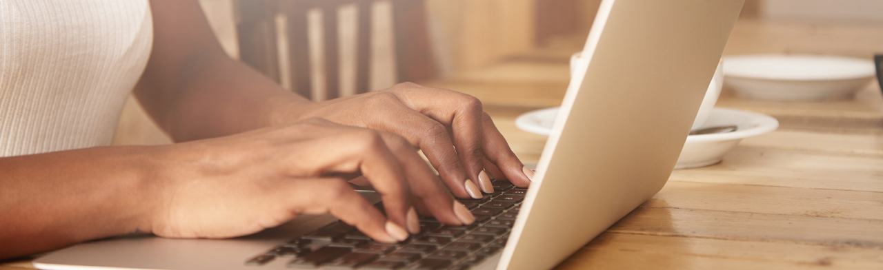 Foto de mãos digitando em um notebook.