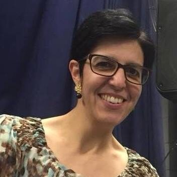 Foto de Andrea Luize sorrindo, uma mulher de pele branca cabelos pretos curtinhos e óculos de grau