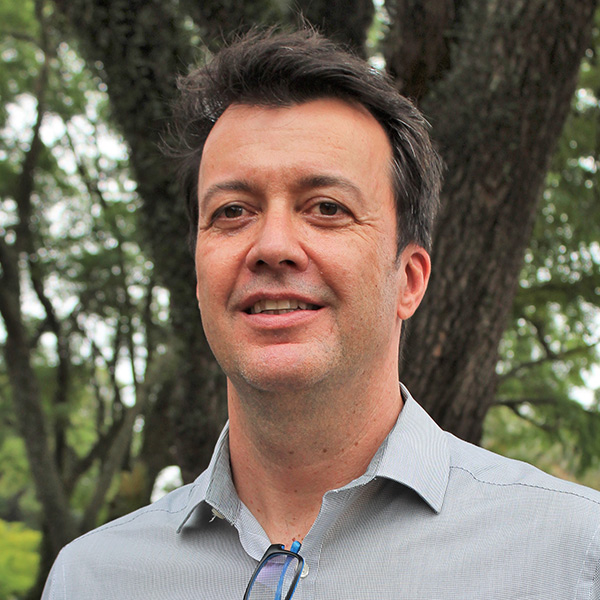 Foto de Ricardo Vilela, um homem de pele branca e cabelos castanhos e curtos sorrindo.