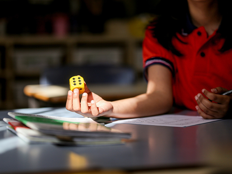 Foto em destaque de um dado na mão de uma garota