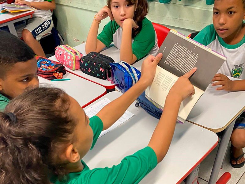 Foto de quatro crianças diversas lendo um livro