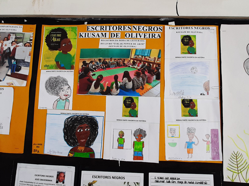 Foto de mural com diversos cartazes com desenhos e colagens de pessoas negras