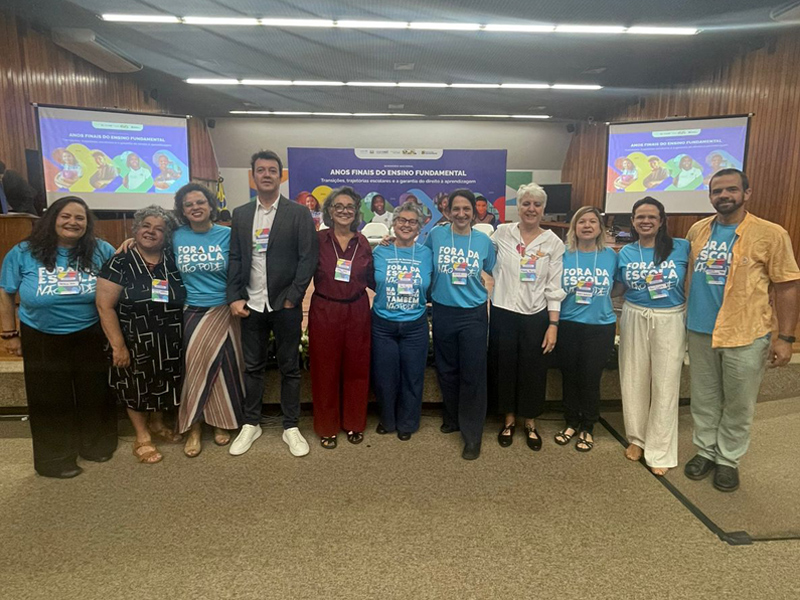 Foto de um grupo diverso de pessoas da Roda Educativa posando lado a lado. Alguns usam camisetas azuis do evento do UNICEF, com os dizeres "Fora da escola não pode".