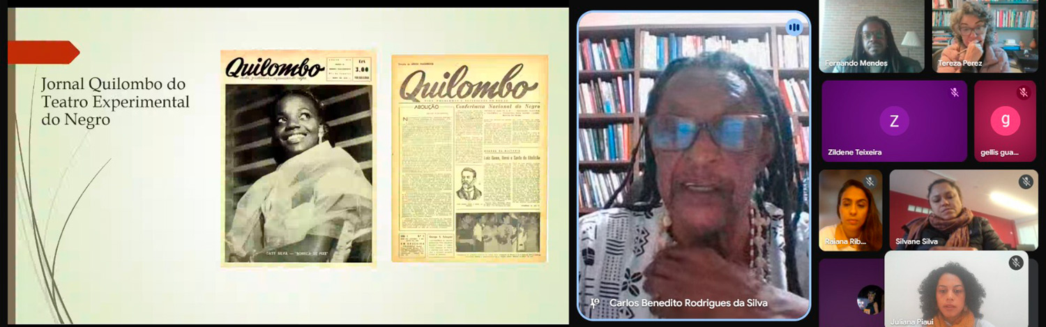 Print da gravação de uma aula magna feita pelo Google meet com Carlos Benedito Rodrigues da Silva, um homem negro de cabelos com tranças, fazendo uma apresentação. Há também outras pessoas na tela.
